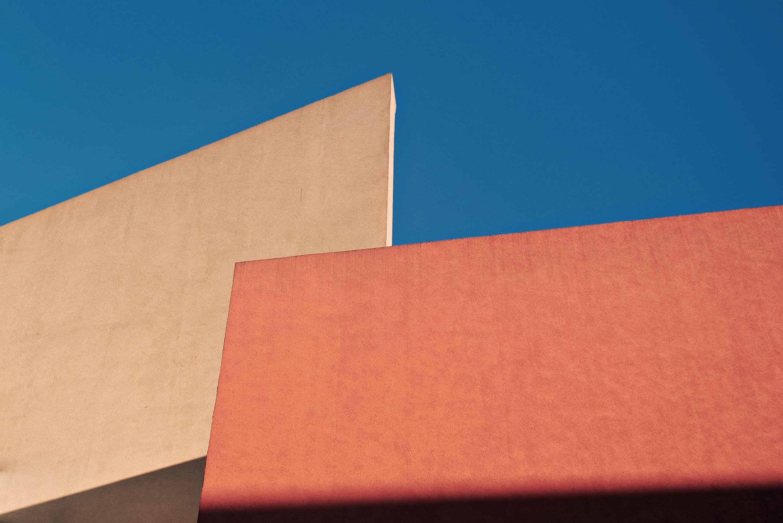Abstract terra cotta and cream walls against blue sky